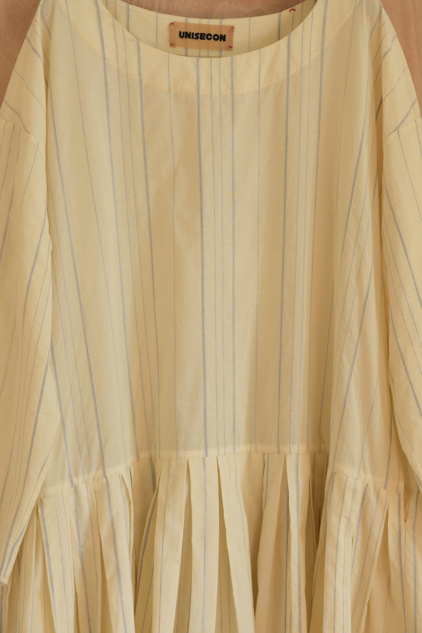 Close-up of cream base cotton with woven blue threads and soft neckline