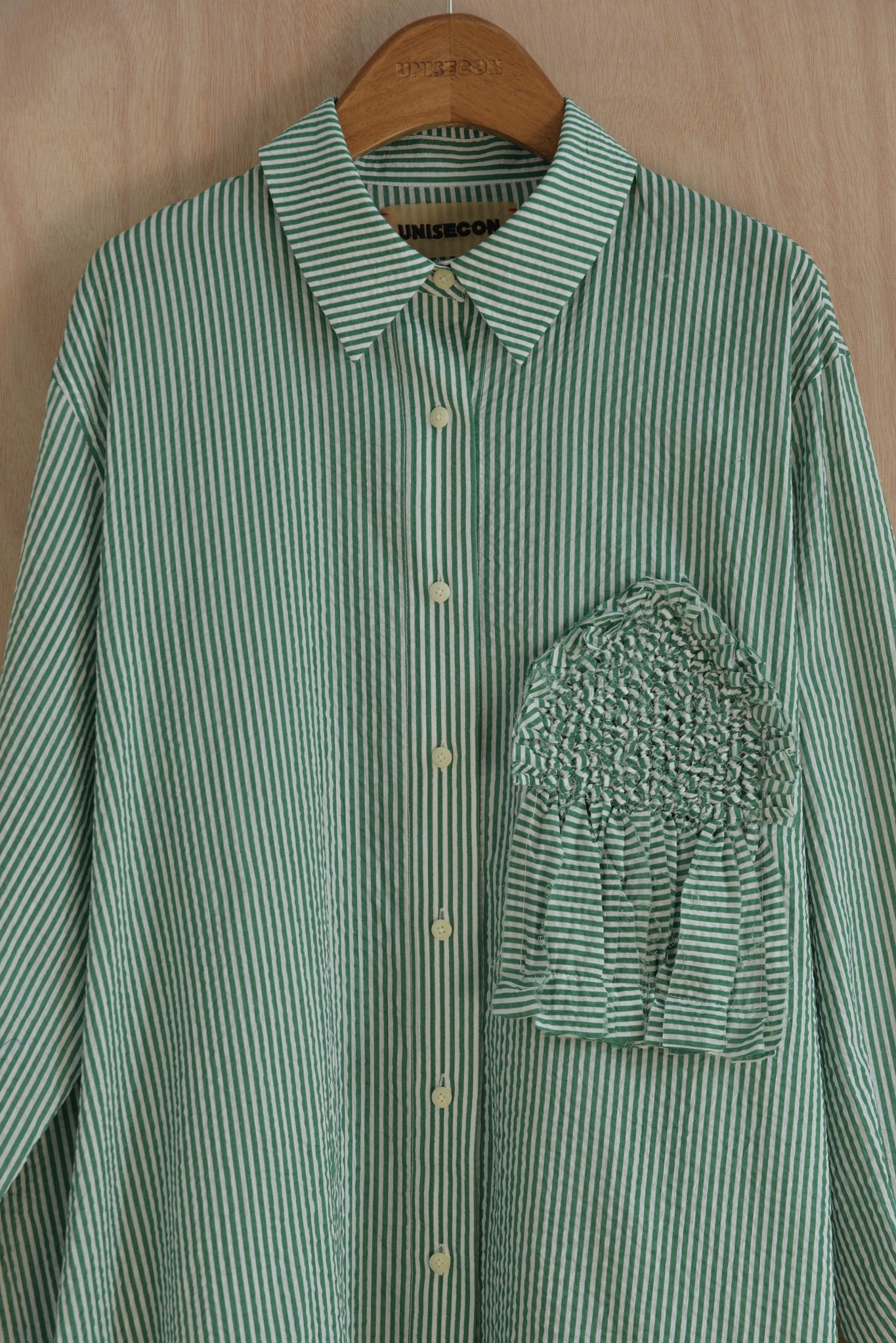 Close-up of house-shaped hand-woven chest detail and striped collar in soft cotton