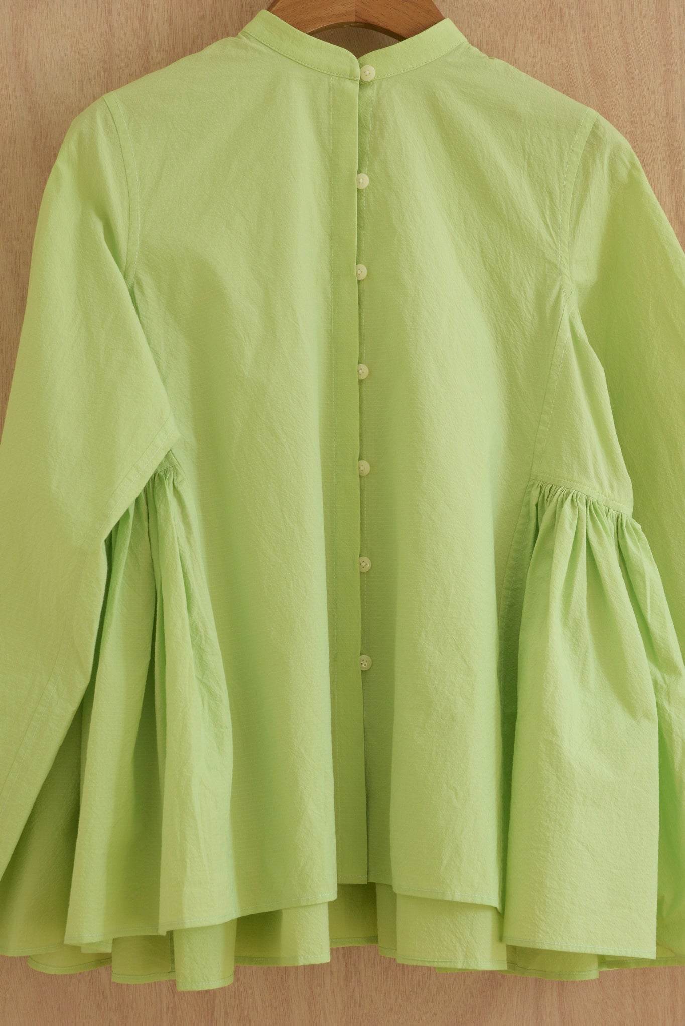 Close-up of hand-gathered pleats on sleeve and light green cotton texture