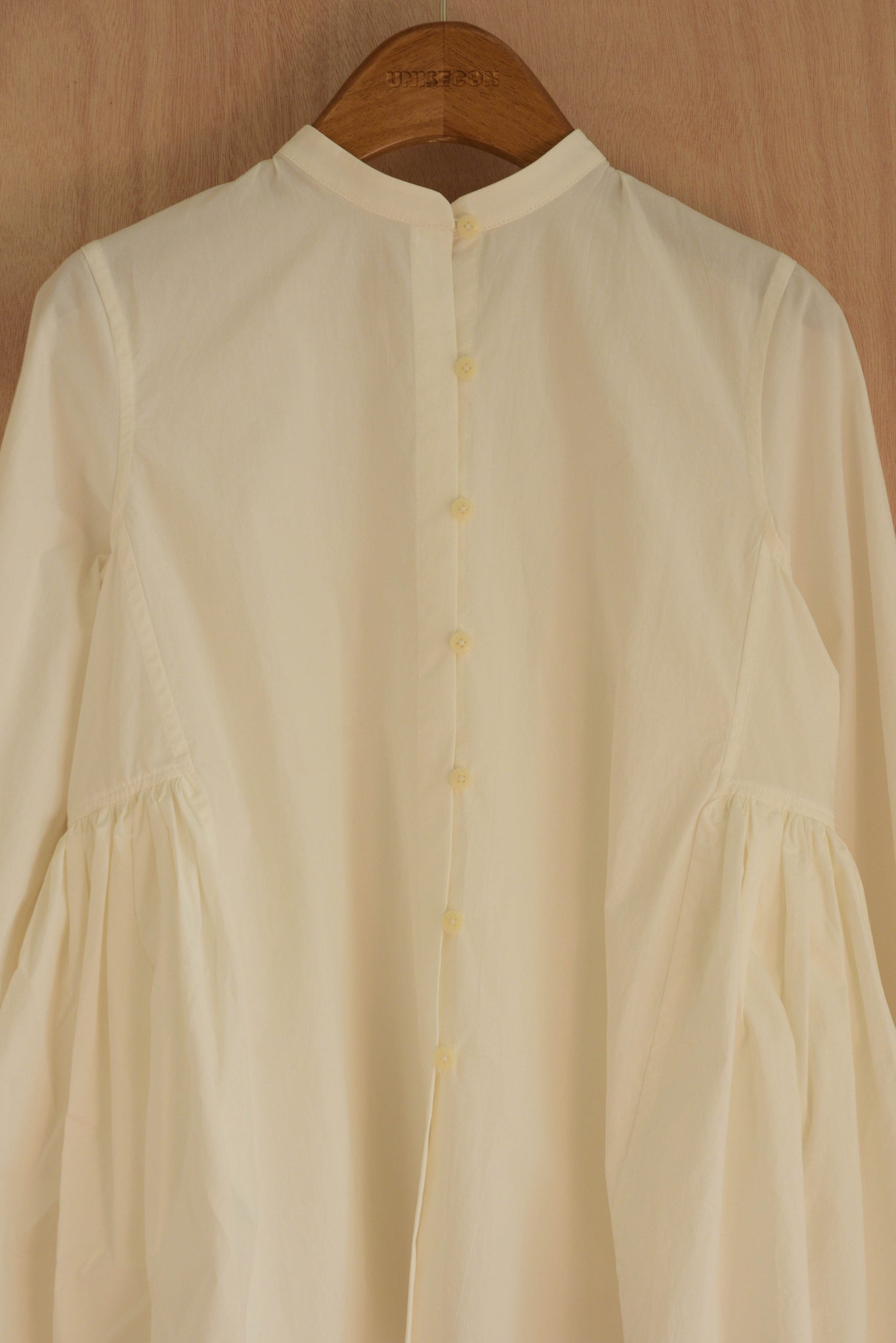Close-up of high neckline and hand-gathered sleeve pleats in white cotton