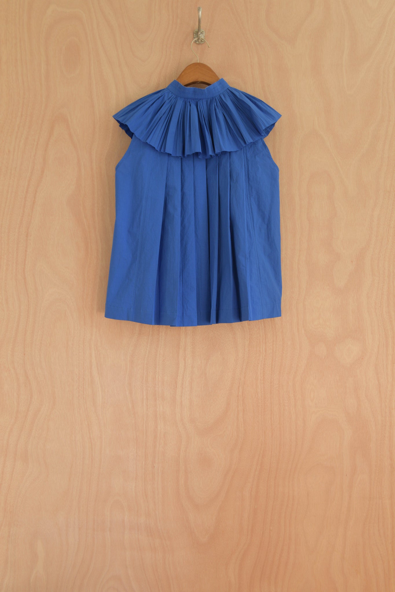 Back view of Rea Top in blue, featuring structured pleats for volume.