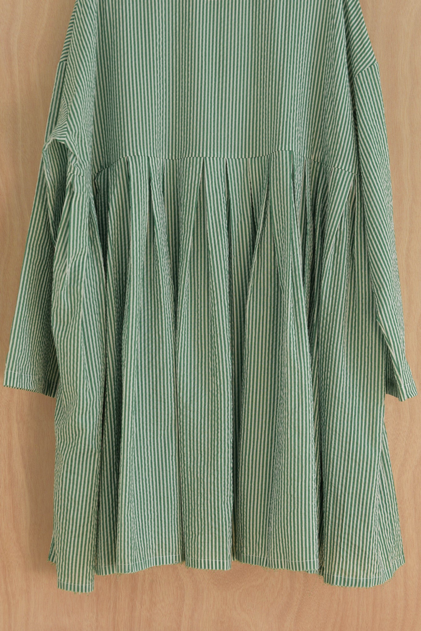 Close-up of hand-gathered hem and puckered cotton texture in green and white