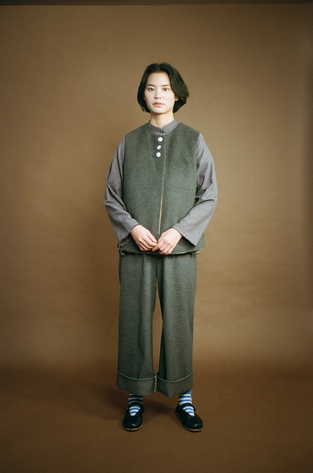 Person wearing a gray outfit with a brown background