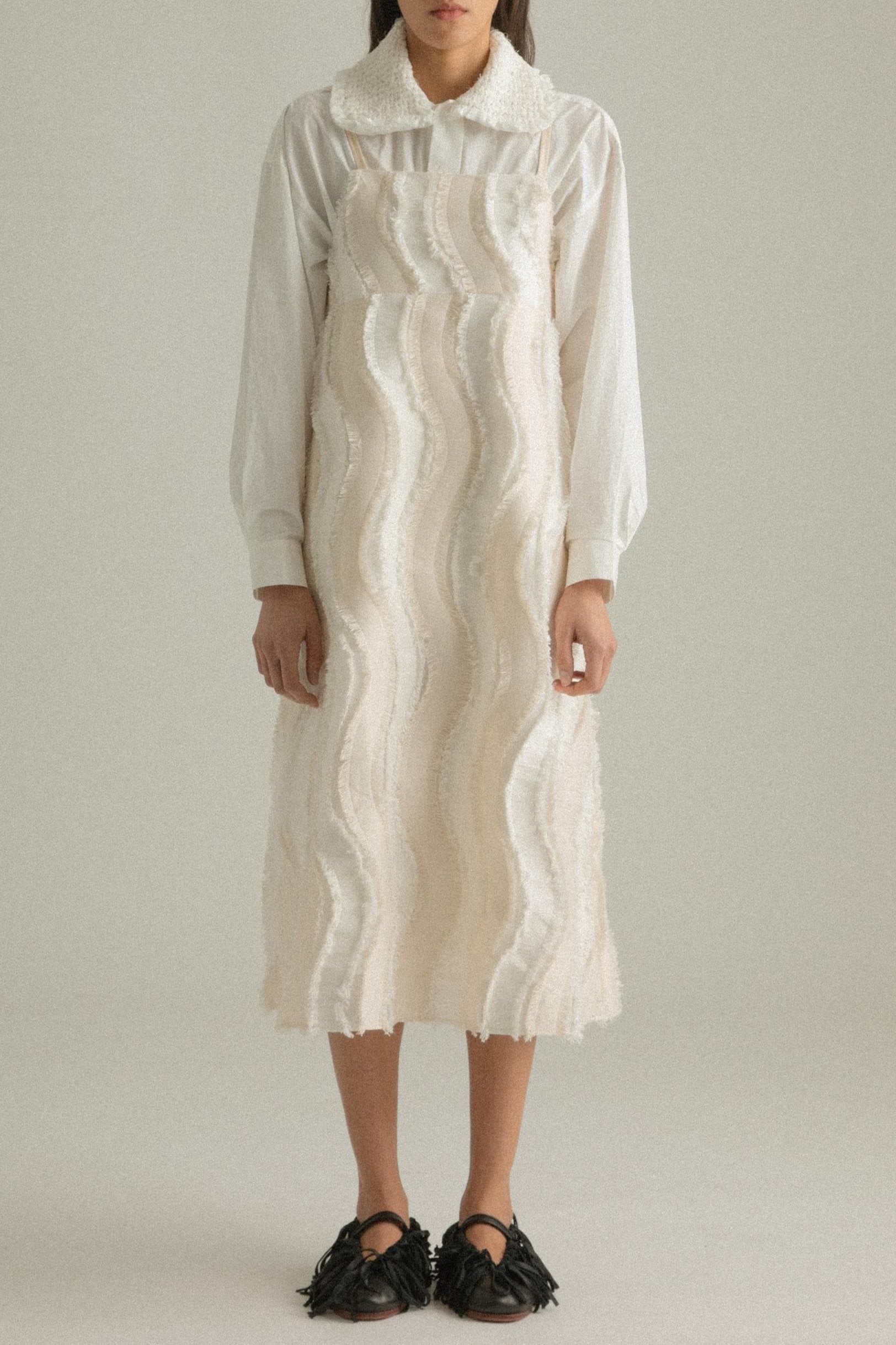 A model wearing the Lena Dress, featuring a wave-like patchwork design made from a blend of cotton, acrylic, and polyester. The model is shown in front, side, and back views to highlight the dress’s texture and A-line silhouette.