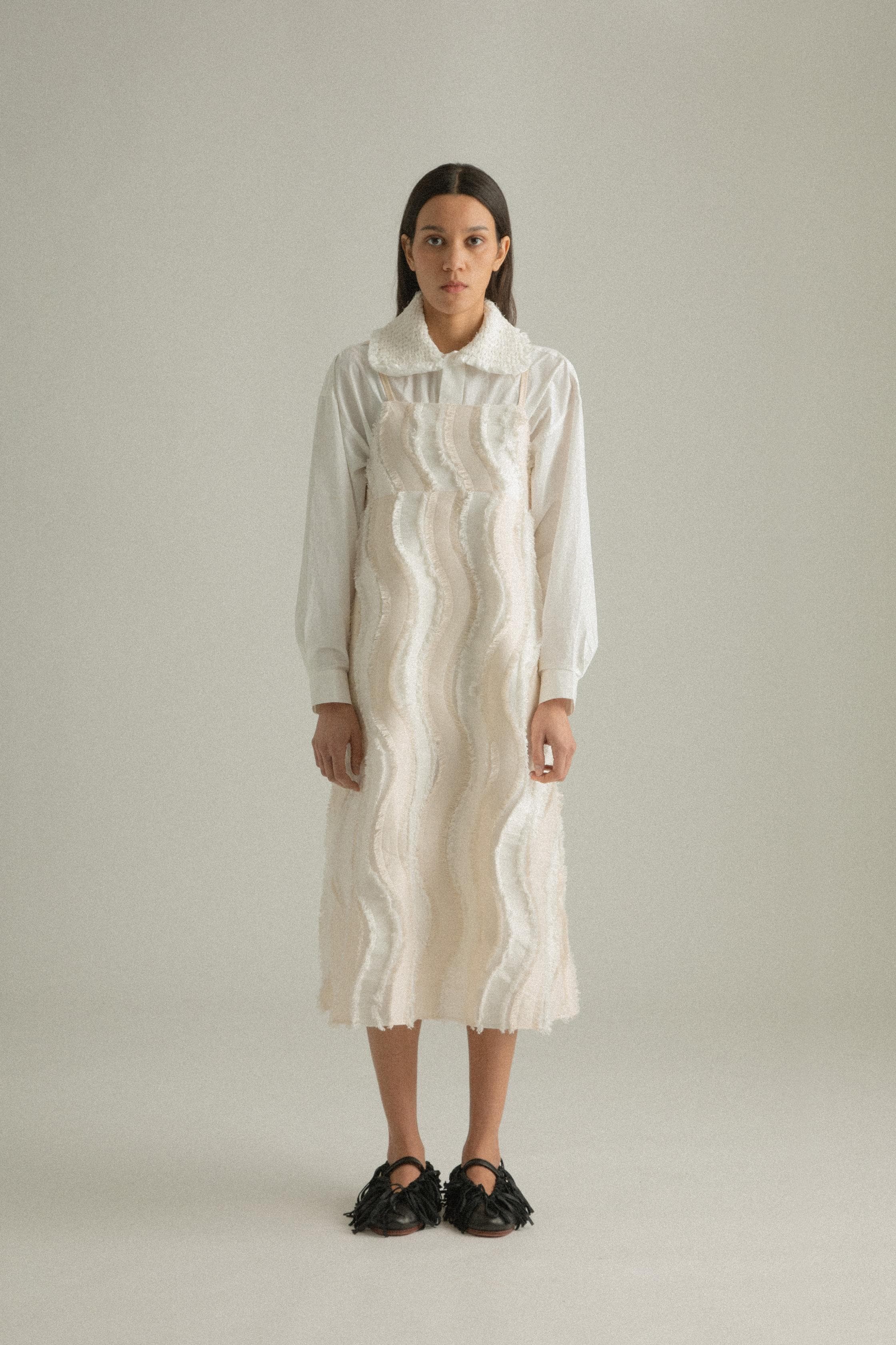 A model wearing the Lena Dress, featuring a wave-like patchwork design made from a blend of cotton, acrylic, and polyester. The model is shown in front, side, and back views to highlight the dress’s texture and A-line silhouette.