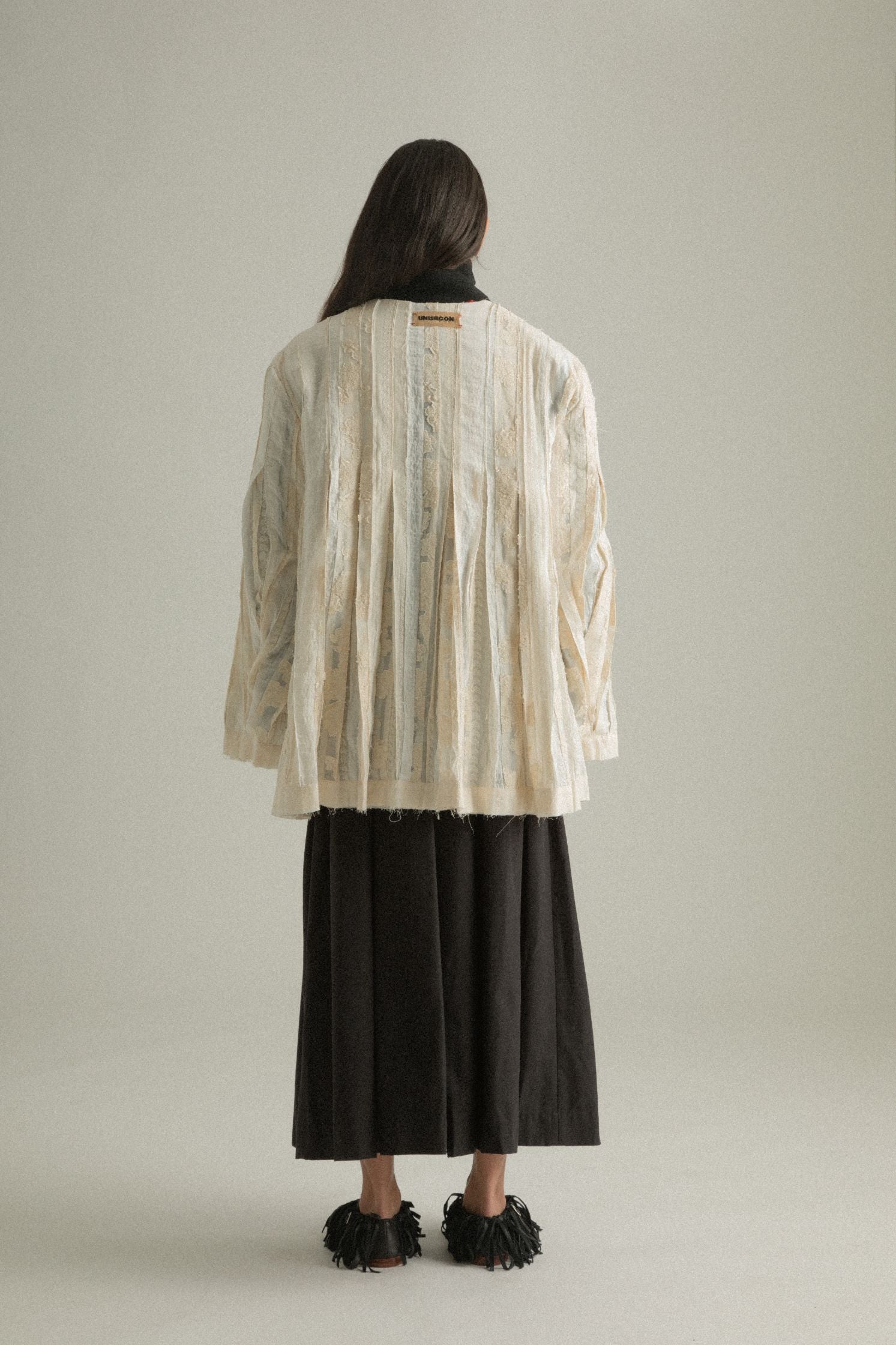 Back view of the Martha Coat on the cream patchwork side, featuring layered textures and subtle pleats.