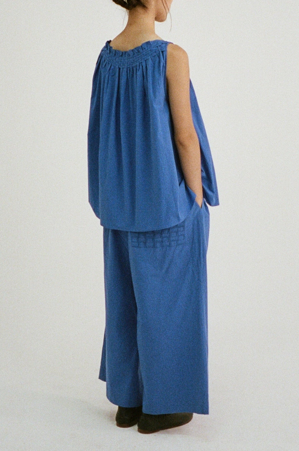 Styled image of the Olga Top in blue, paired with matching wide-leg trousers, showing movement and texture.