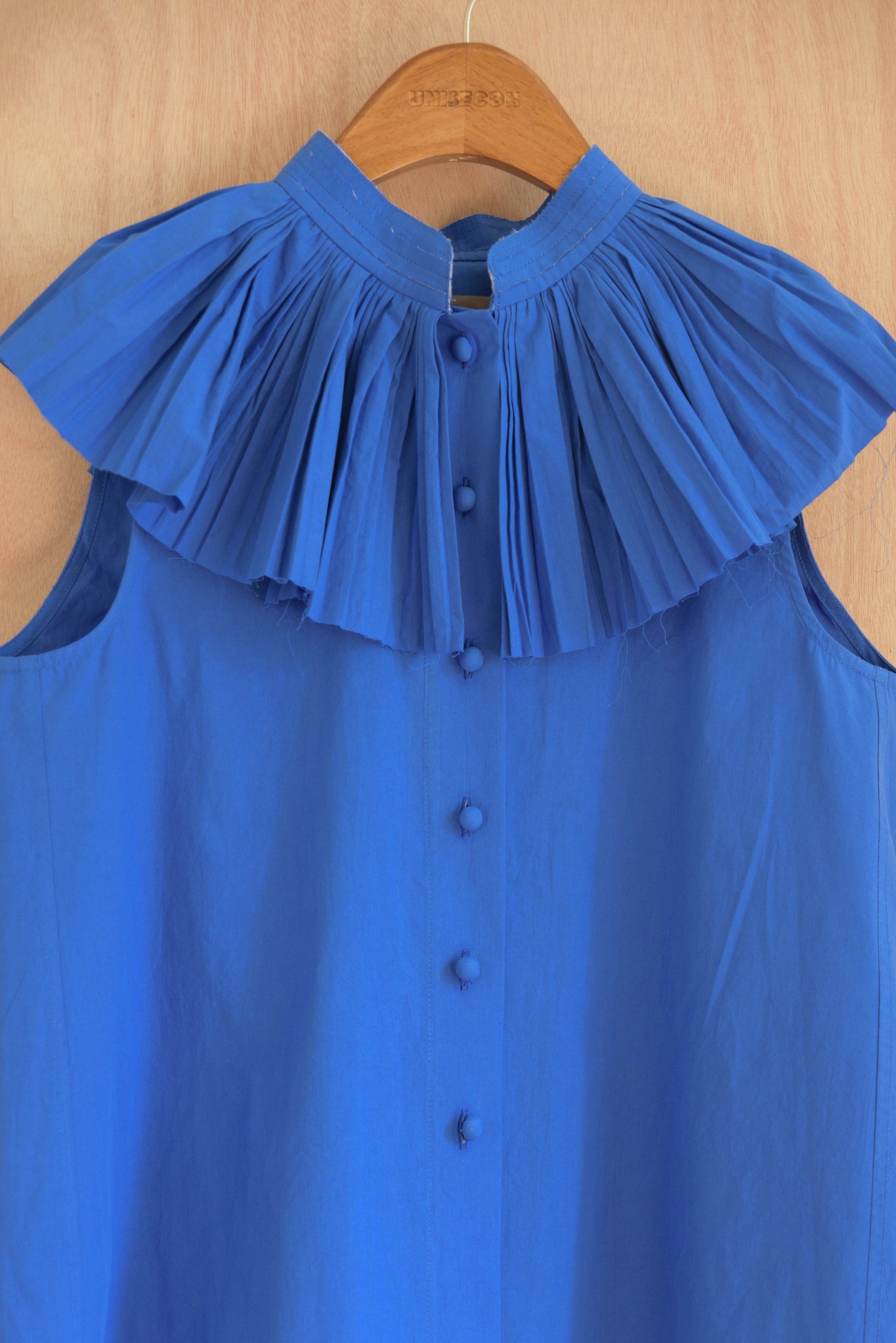 Close-up of Rea Top in blue, highlighting the pleated collar.