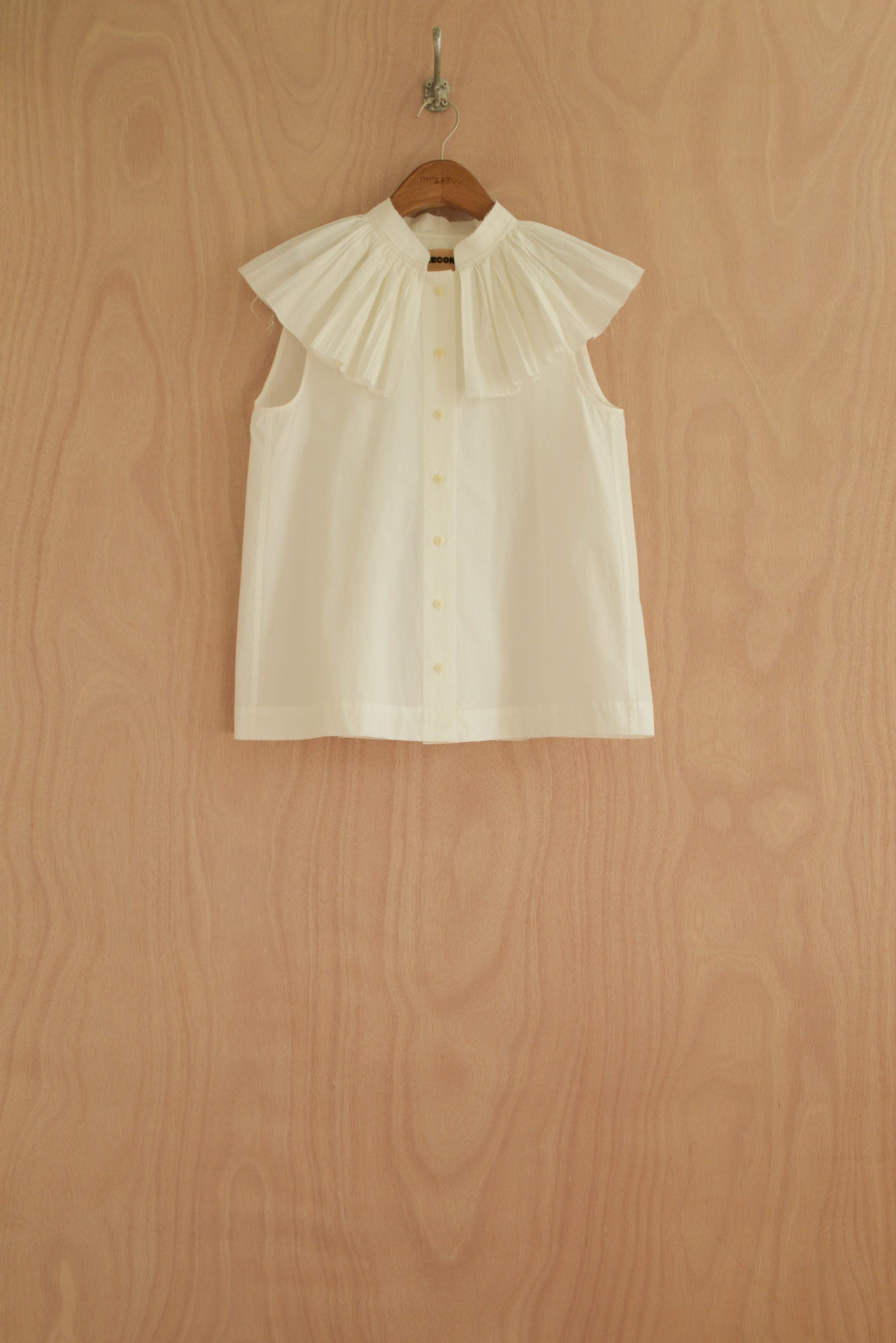 Rea Top in white, organic cotton with a structured pleated collar and sleeveless design.