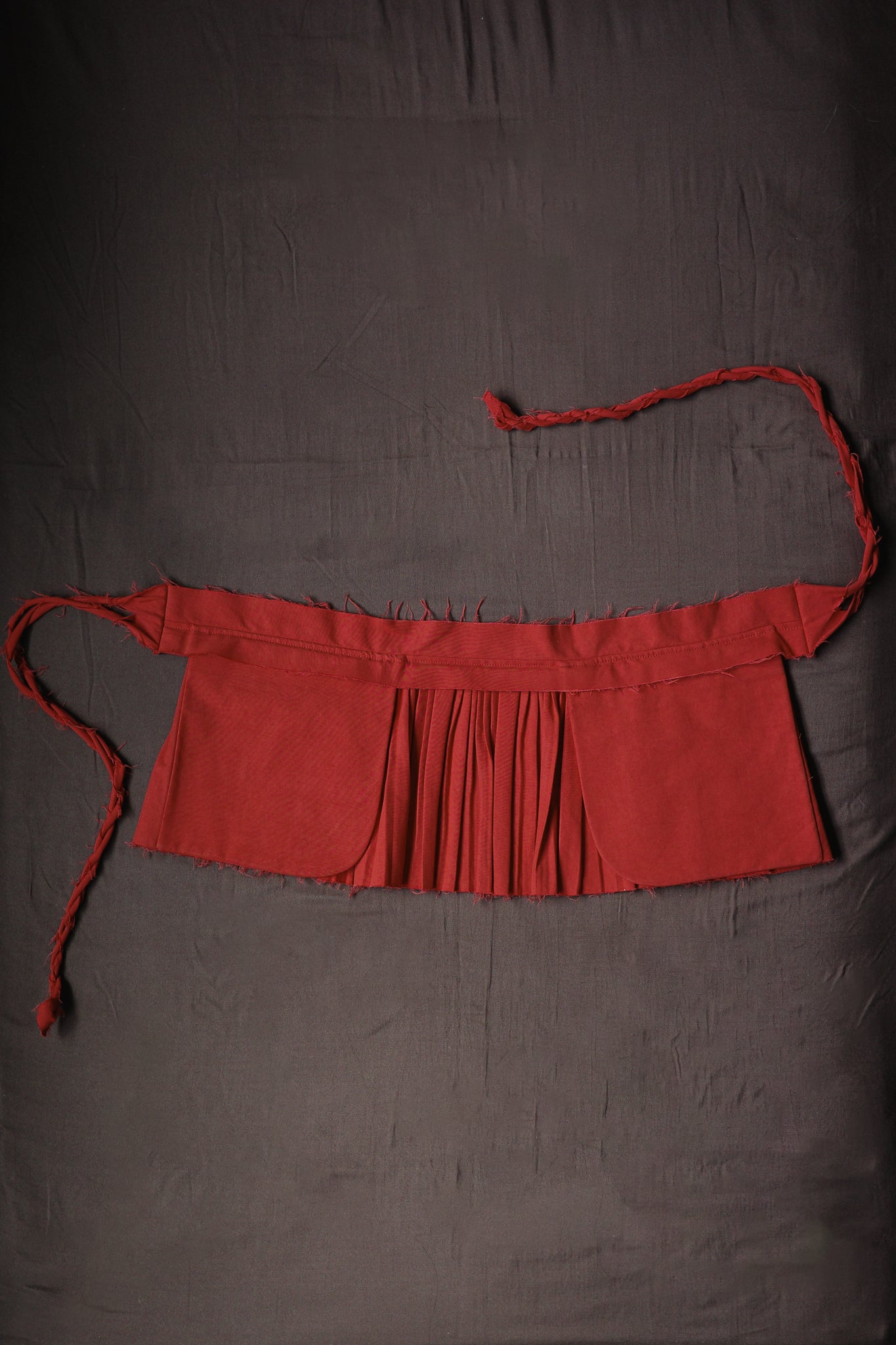  Red Goma apron with structured waistband and pleated construction.