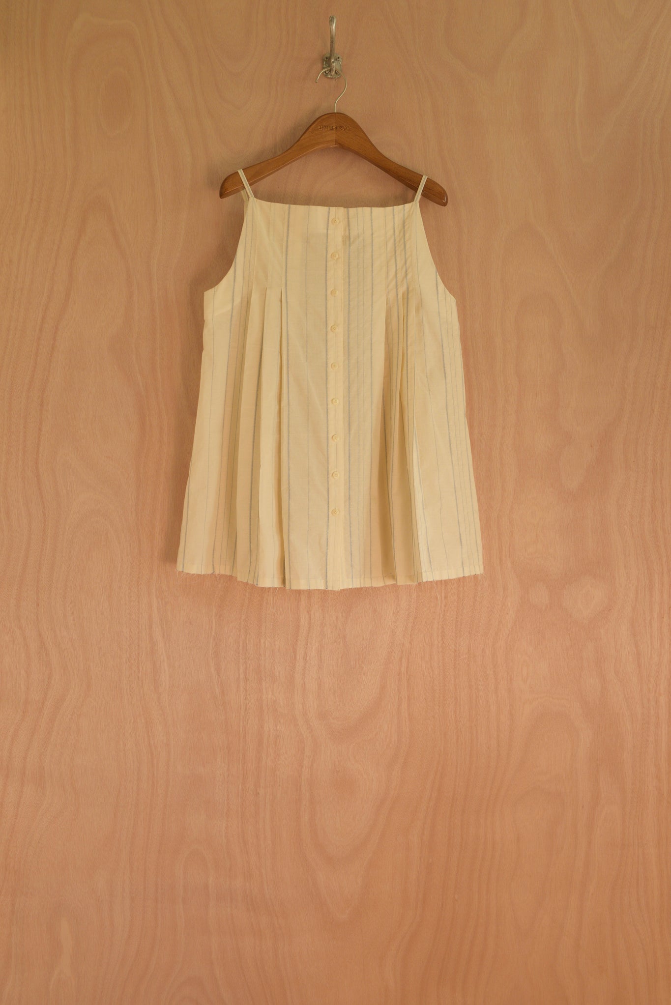 Front view of the Sharrin Top in cream cotton with structured pleats.