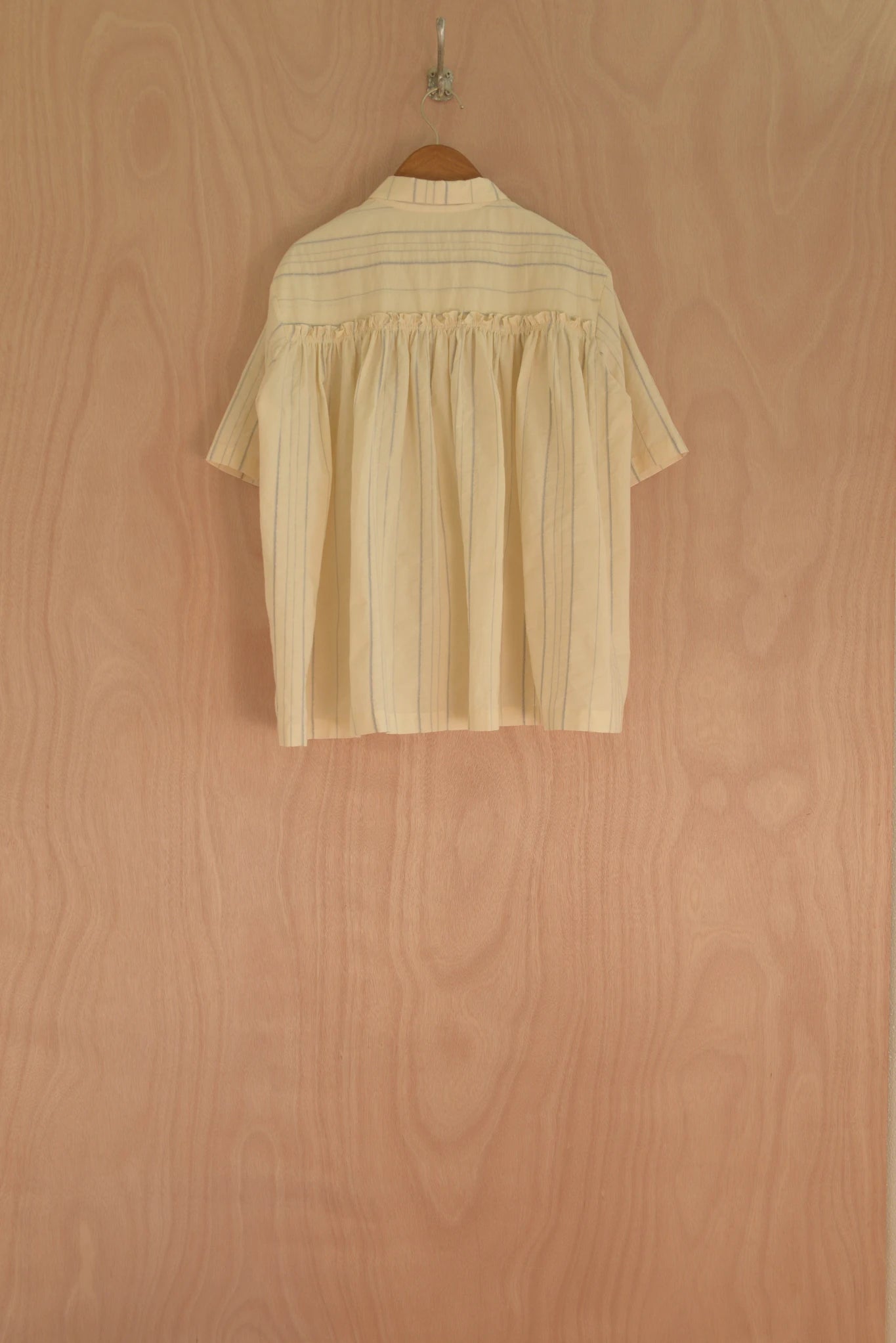 Beige blouse on a hanger against a wooden wall