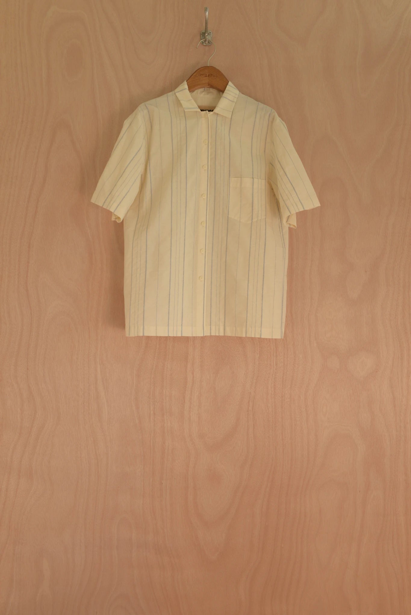 Beige striped shirt on a hanger against a wooden background